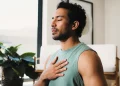 Man practicing deep breathing with his hand on his chest to promote better sleep and overall men's health.