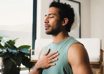 Man practicing deep breathing with his hand on his chest to promote better sleep and overall men's health.